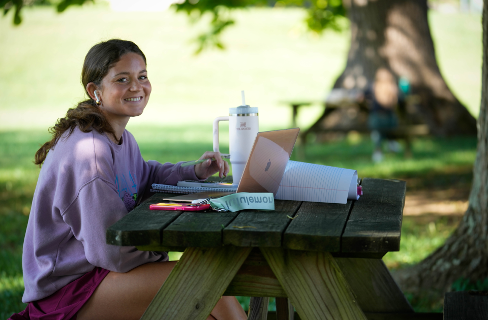 A student studying at a picnic table. 